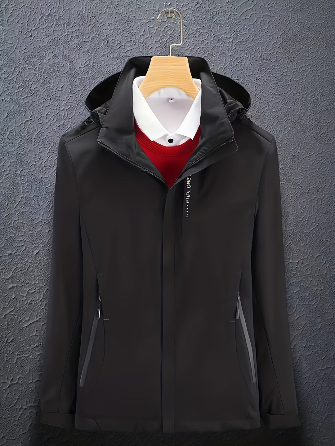Giacca nera elegante con cappuccio, appesa su gruccia, sopra camicia bianca e maglione rosso. Moda uomo, abbigliamento invernale, stile casual.