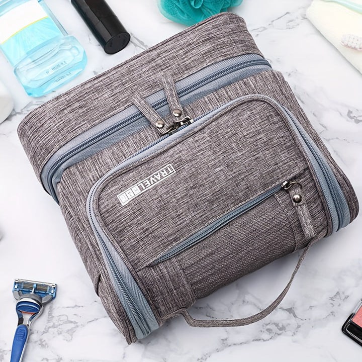 Borsa da viaggio grigia in tessuto, con zip multiple, su sfondo di marmo. Ideale per organizzare articoli da toeletta e accessori da viaggio.