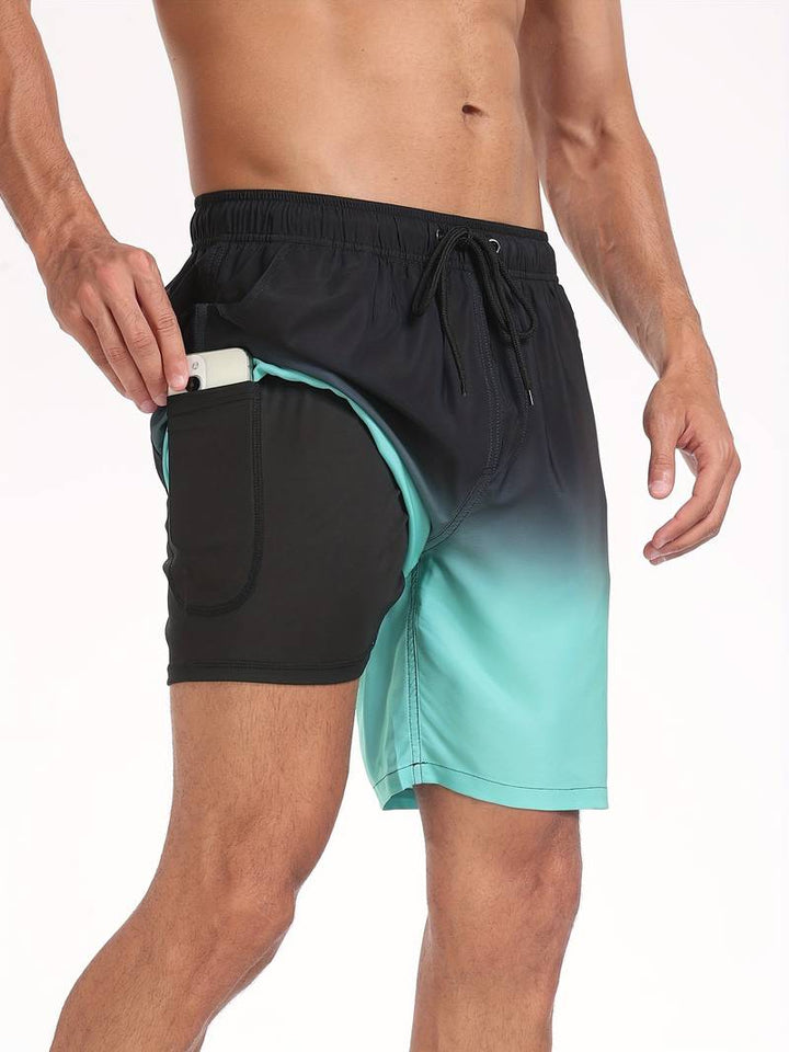 Uomo in costume da bagno sfumato nero e verde acqua con tasca laterale, inserisce uno smartphone. Costume mare uomo, moda estiva, pratico e moderno.