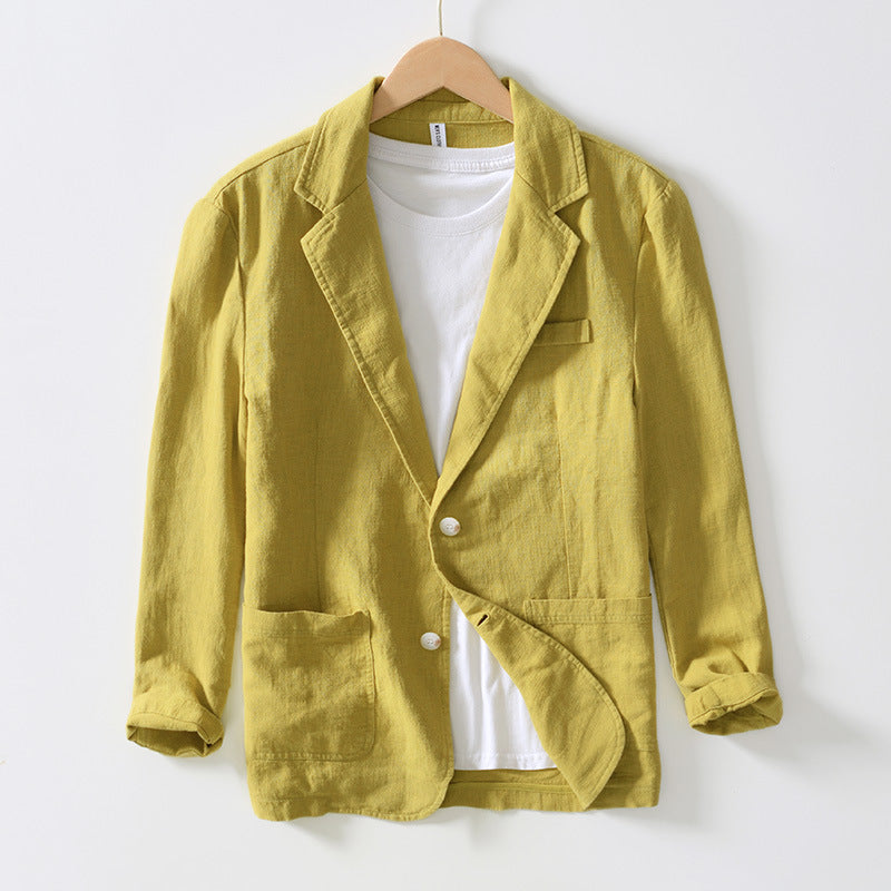 Giacca blazer gialla da uomo in lino, stile casual, con tasche frontali e bottoni bianchi, appesa su gruccia, sopra t-shirt bianca.