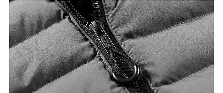 Giacca invernale imbottita grigia con cerniera nera, dettaglio tessuto resistente e cuciture rinforzate. Abbigliamento caldo e impermeabile.