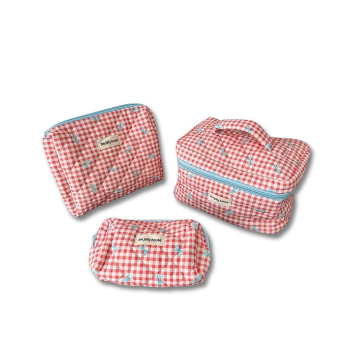 Set di tre beauty case a quadretti rossi e bianchi con cerniera azzurra, ideale per viaggi. Design elegante e pratico per organizzare cosmetici.