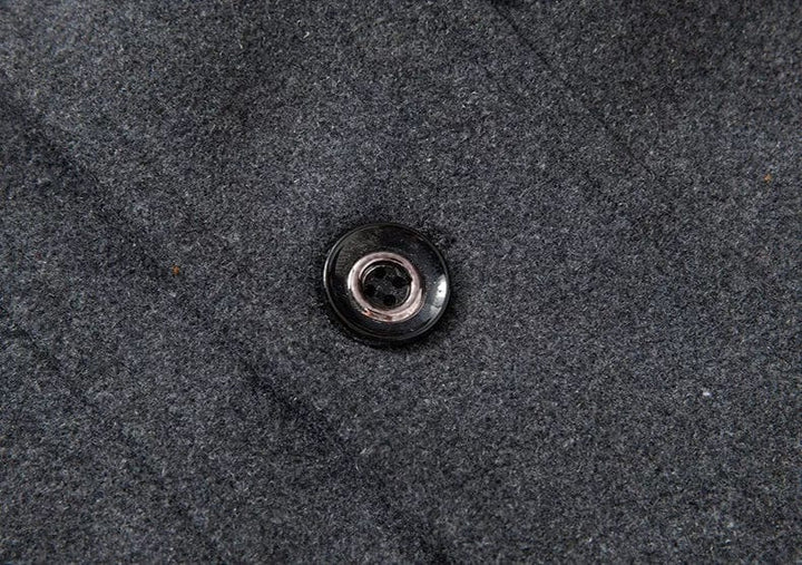 Pulsante nero su tessuto grigio in lana, dettaglio moda abbigliamento invernale, texture elegante e raffinata, ideale per cappotti e giacche.