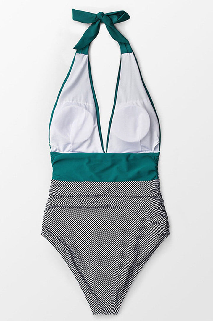 Costume intero donna a righe bianche e nere, scollo profondo, con dettagli verde acqua. Elegante e alla moda per l'estate.