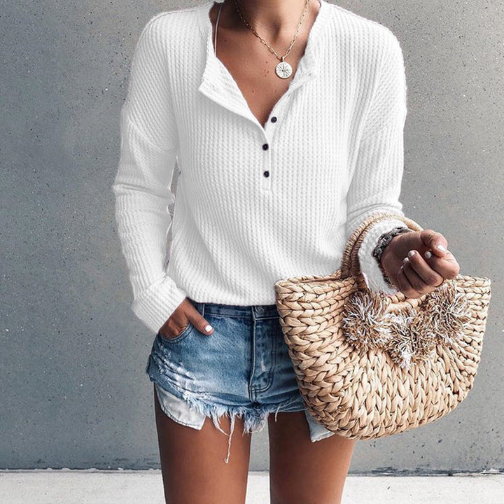 Donna con maglione bianco a coste, shorts di jeans e borsa di paglia intrecciata. Moda casual estiva, abbigliamento femminile trendy.