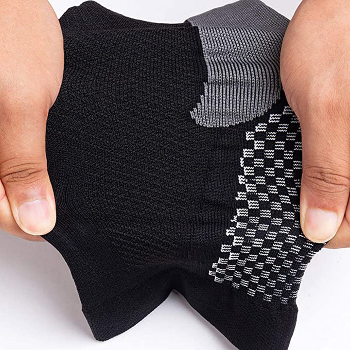 Mani che tengono calzini sportivi neri e grigi, tessuto traspirante e antiscivolo, ideale per attività fisica, comfort e prestazioni ottimali.