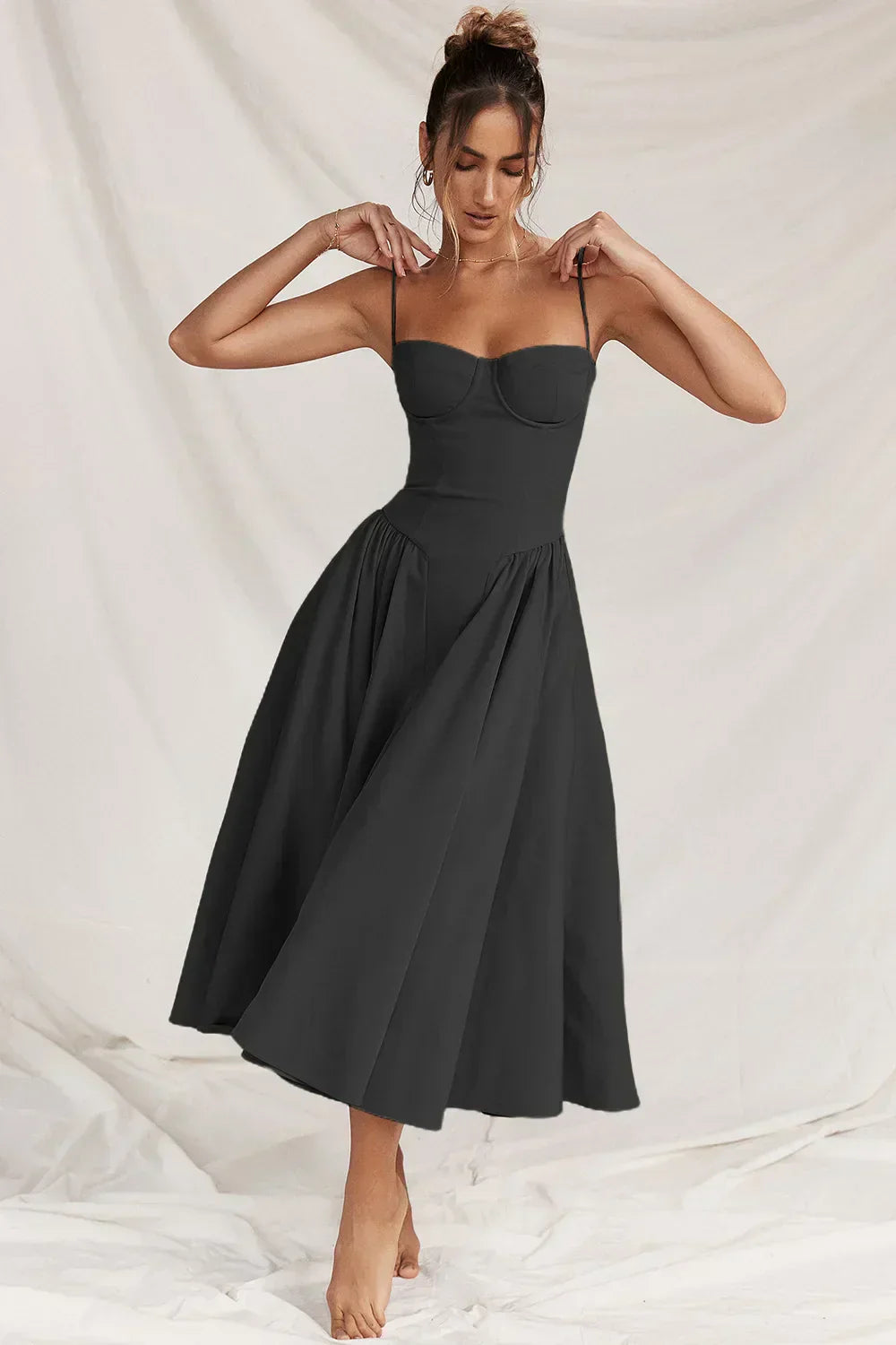 Abito nero elegante da donna, lunghezza midi, senza maniche, con spalline sottili e gonna ampia. Perfetto per eventi formali e serate speciali.