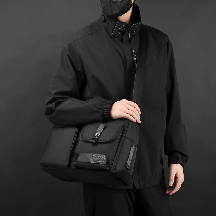 Uomo con giacca nera indossa borsa a tracolla nera elegante, tasche multiple, design moderno. Accessorio moda maschile, stile urbano.