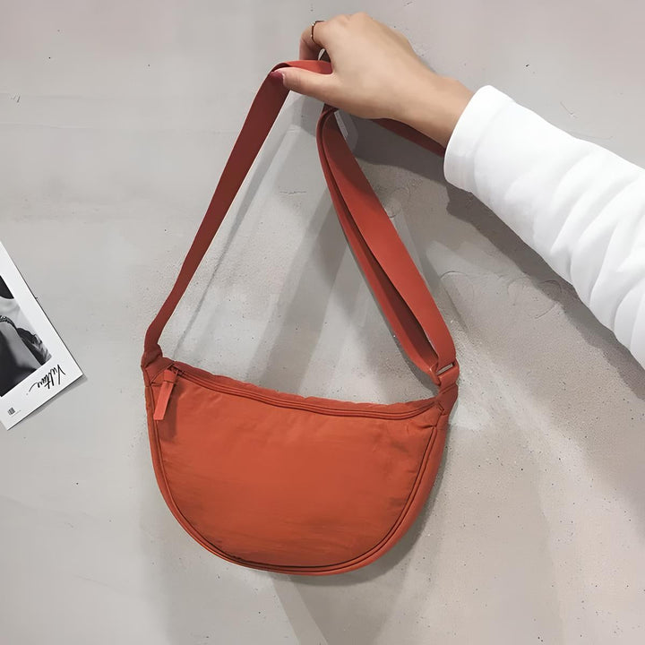 Borsa a tracolla arancione, design minimalista, tessuto leggero, chiusura con zip, ideale per moda casual e viaggi. Accessorio trendy unisex.
