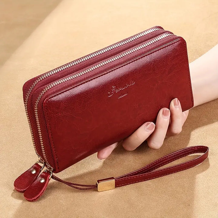 Portafoglio donna in pelle rossa con doppia cerniera, cinturino da polso e dettagli dorati. Elegante accessorio moda, ideale per organizzare carte e contanti.