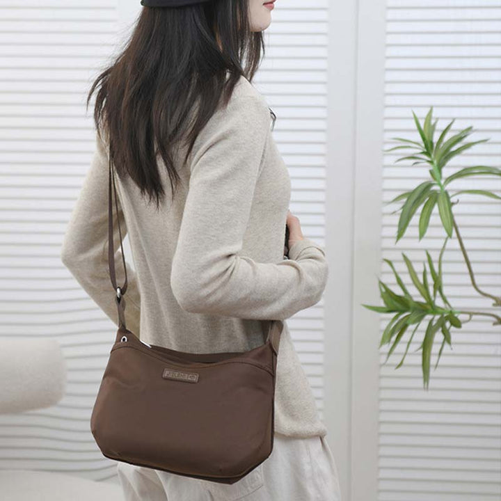 Donna con borsa a tracolla marrone, design elegante e moderno, indossa maglione beige. Accessorio moda femminile, perfetto per uso quotidiano.