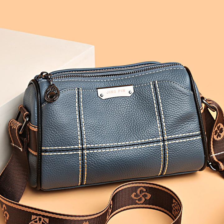 Borsa a tracolla in pelle blu con cuciture bianche, cerniera superiore e tracolla regolabile marrone. Design elegante e moderno per donna.