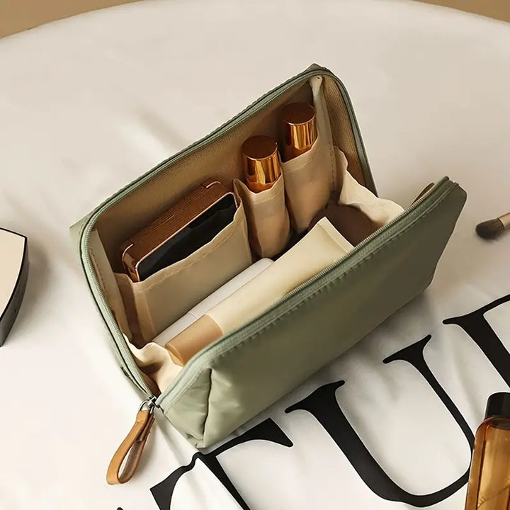 Astuccio da viaggio verde aperto con scomparti, contenente cosmetici e accessori. Organizzatore compatto per trucco, ideale per viaggi.