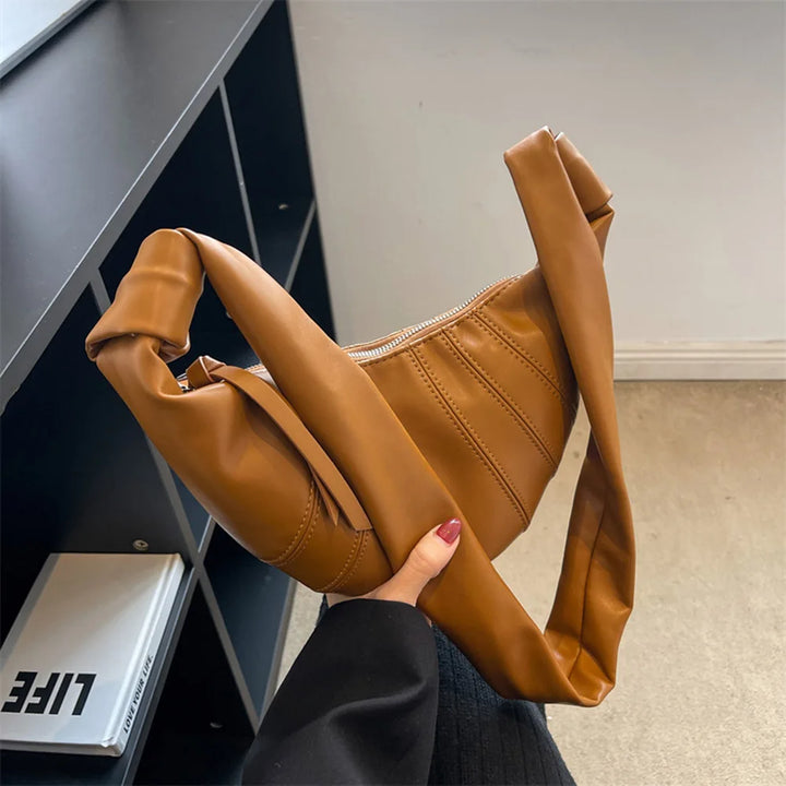 Borsa a tracolla in pelle marrone, design moderno e minimalista, su sfondo neutro. Accessorio moda donna, elegante e versatile.