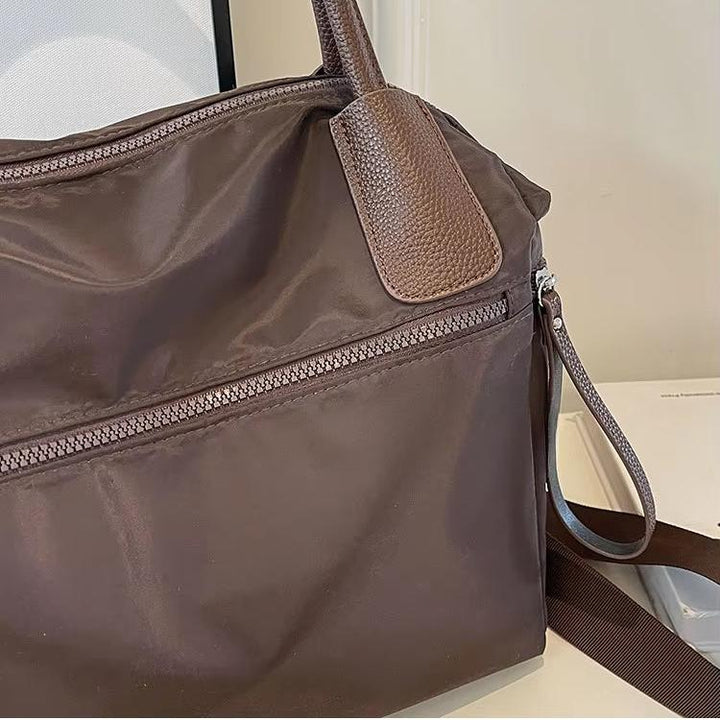 Borsa a tracolla marrone in nylon con cerniera, manici in pelle, design elegante e funzionale, ideale per uso quotidiano e viaggi.