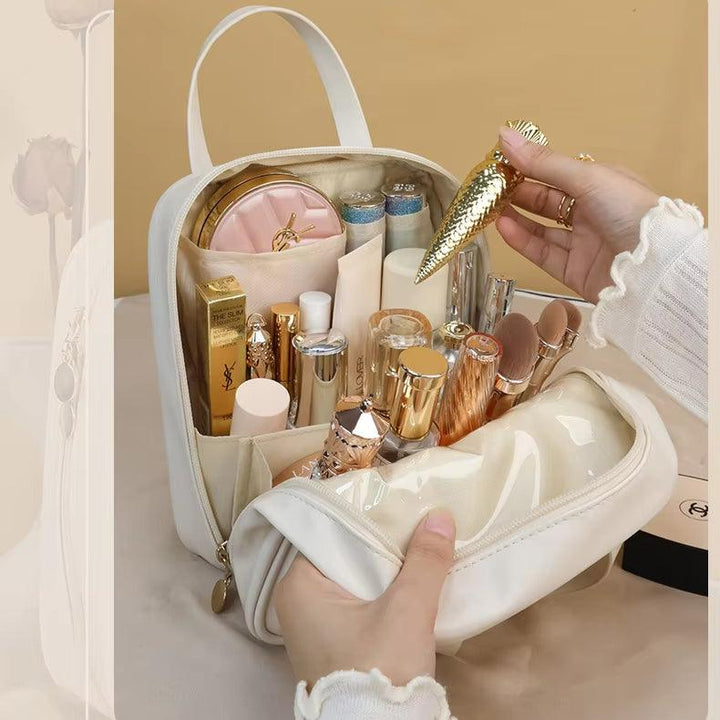 Borsa cosmetica bianca aperta con trucchi di lusso, rossetti, pennelli e accessori dorati. Ideale per organizzare il make-up in viaggio.