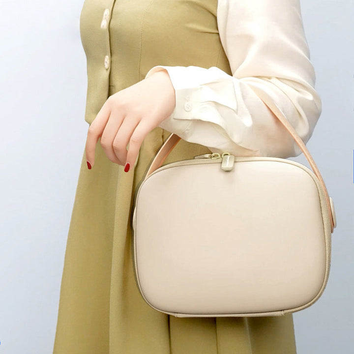 Borsa a tracolla beige elegante, indossata da una donna con abito verde chiaro e camicia bianca. Accessorio moda femminile chic e versatile.