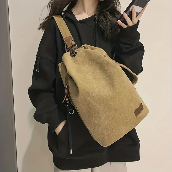 Zaino in tela beige su donna con felpa nera, design casual e spazioso, ideale per scuola o viaggio. Accessorio moda pratico e versatile.