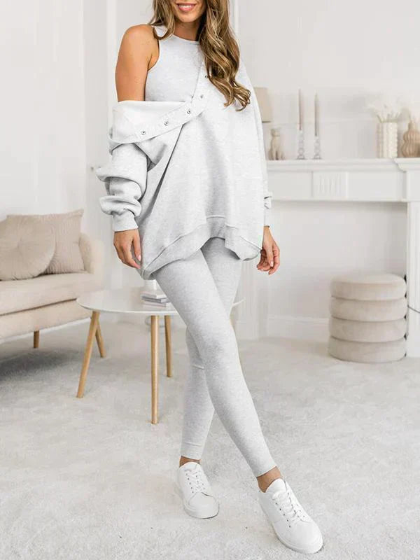 Donna in abbigliamento casual grigio chiaro, felpa oversize e leggings, in salotto moderno. Moda comoda, stile casual, abbigliamento donna.