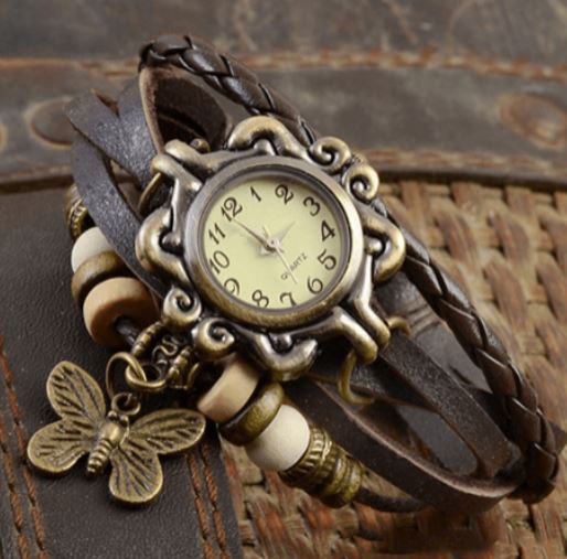 Orologio vintage con cinturino in pelle intrecciata, quadrante antico e ciondolo a farfalla. Design retrò, accessorio moda elegante.