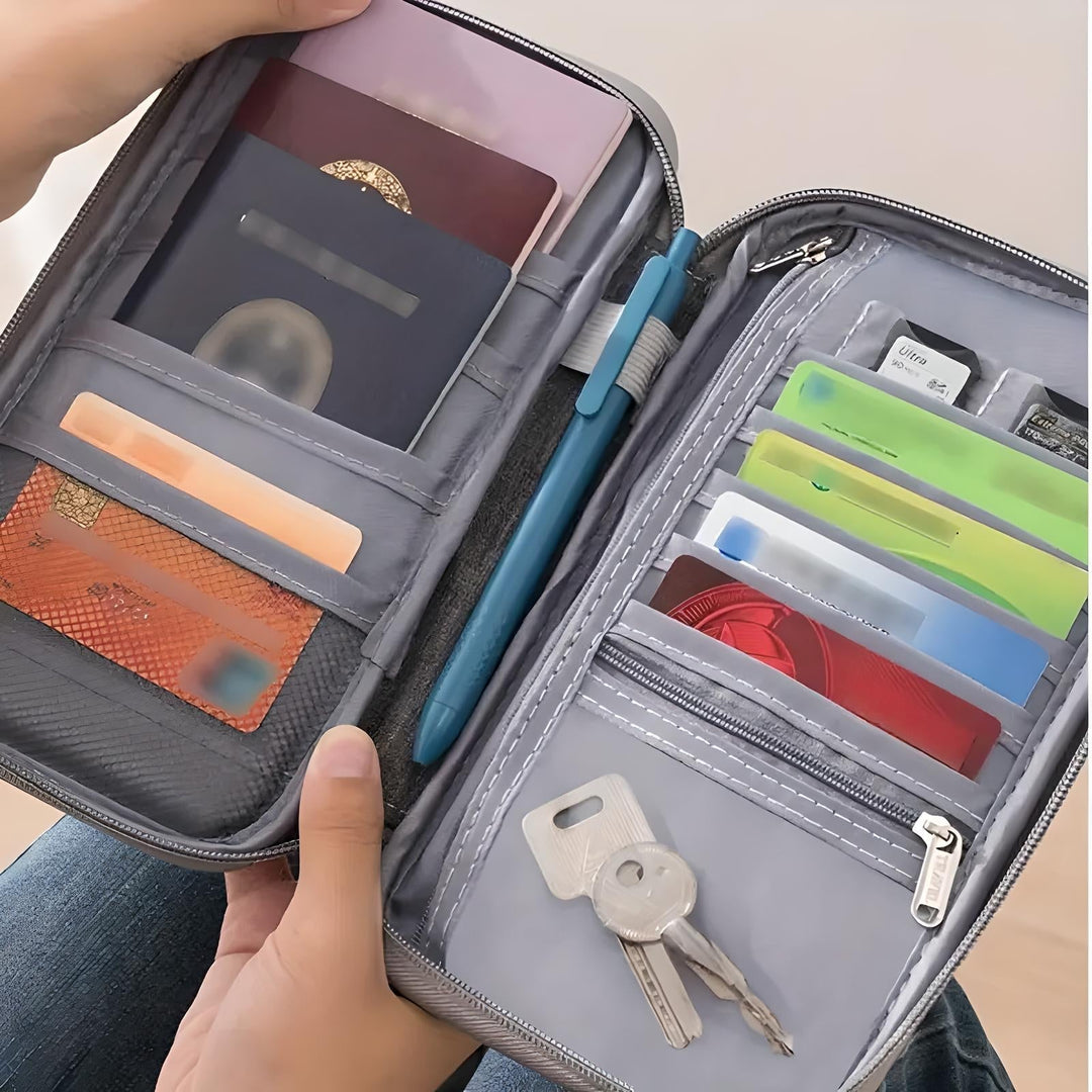 Portafoglio da viaggio grigio aperto con passaporto, carte di credito, penna e chiavi. Organizer compatto per documenti e accessori essenziali.