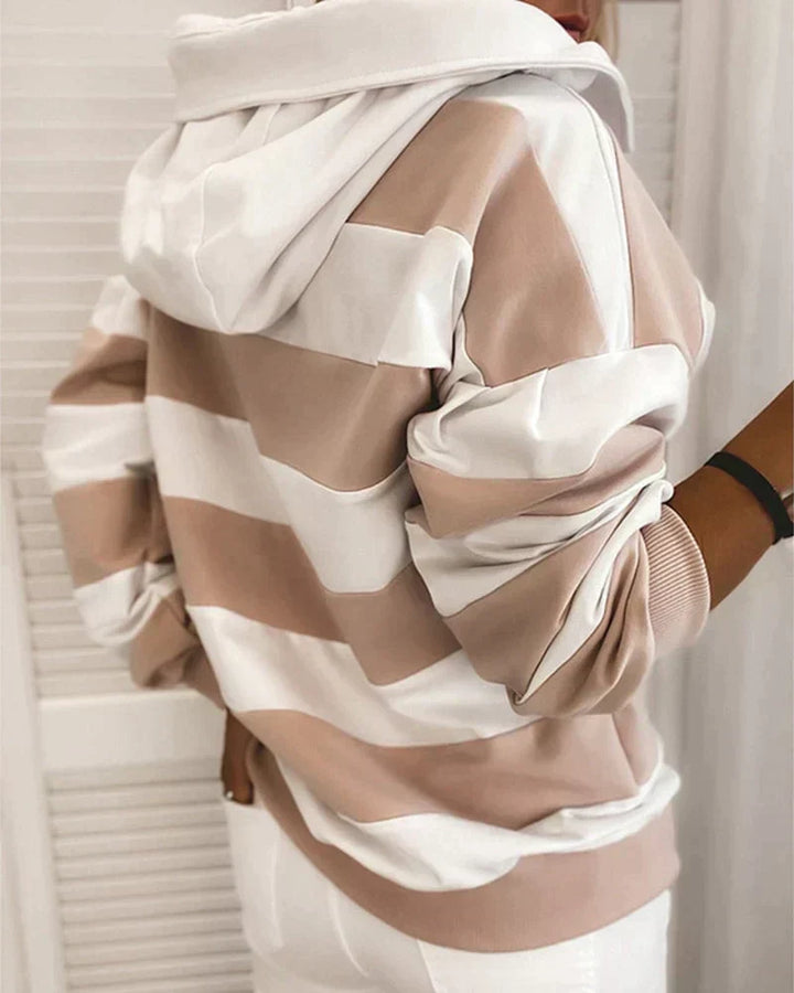 Felpa a righe bianche e beige, con cappuccio, indossata da una persona di spalle. Moda casual, abbigliamento autunnale, stile urbano.