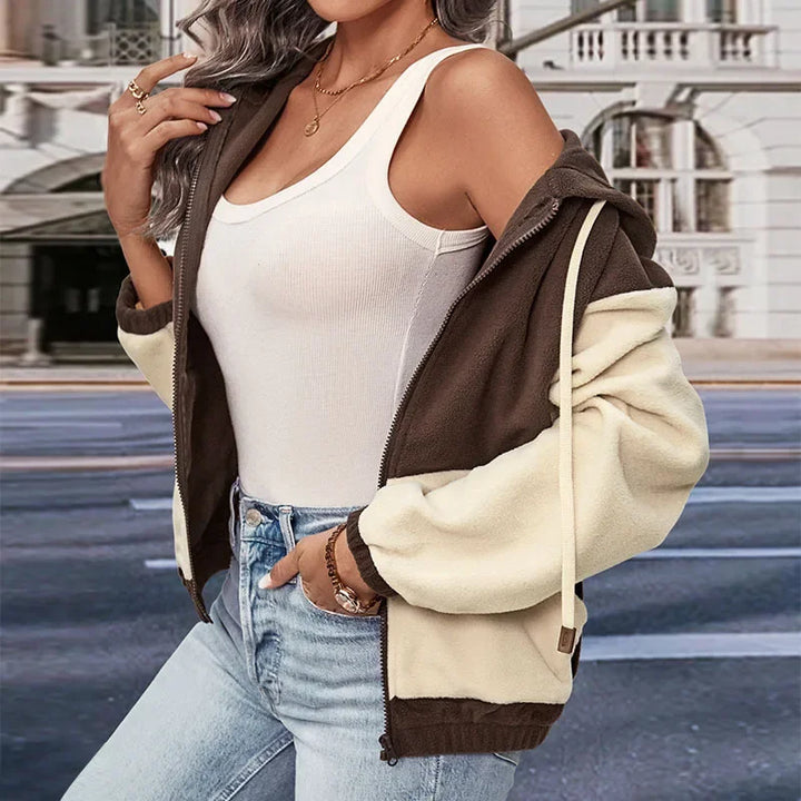 Giacca casual bicolore donna, marrone e beige, con cappuccio, indossata su top bianco e jeans. Moda urbana autunnale, stile casual chic.