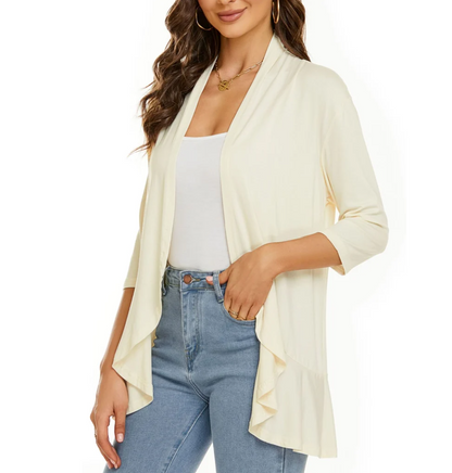 Donna con cardigan aperto color crema, maniche a tre quarti, indossato su top bianco e jeans. Look casual elegante, moda femminile.