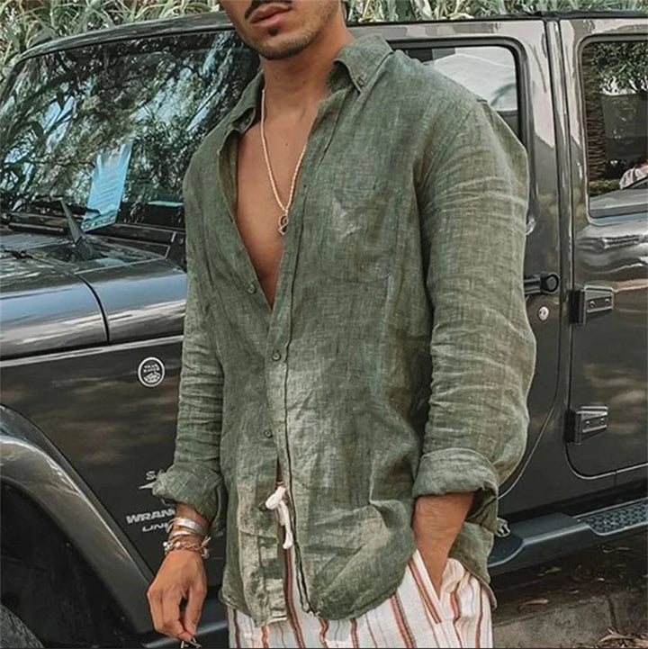 Camicia di lino verde da uomo, stile casual, abbinata a pantaloni a righe, davanti a un SUV grigio. Look estivo elegante e rilassato.