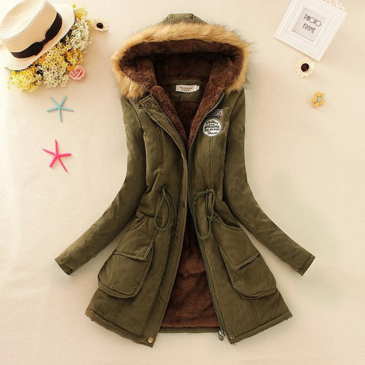 Giacca invernale verde con cappuccio in pelliccia sintetica, chiusura a zip, tasche frontali e dettagli decorativi. Elegante e calda per l'inverno.