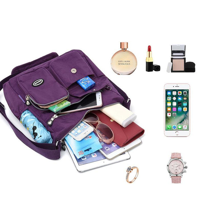Borsa a tracolla viola con tasche multiple, contenente smartphone, portafoglio, occhiali da sole, cosmetici e accessori. Ideale per donna moderna.