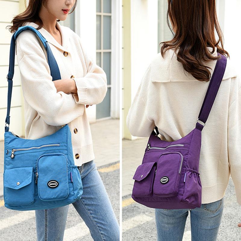 Due borse a tracolla in nylon, una blu e una viola, indossate da due donne. Design casual, tasche multiple, ideali per uso quotidiano e viaggi.