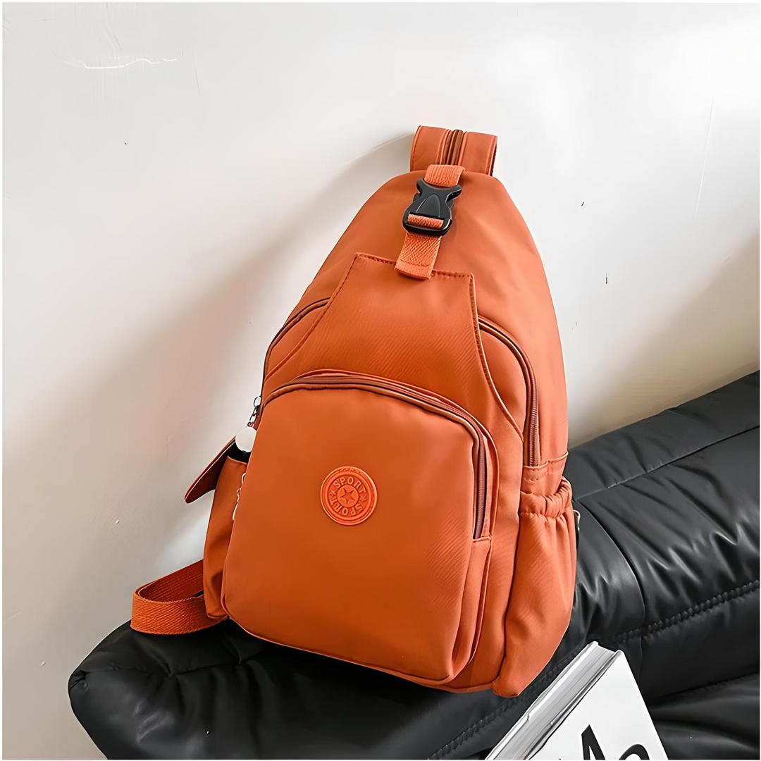 Zaino a tracolla arancione su divano nero, design moderno, tasche multiple, ideale per viaggi e uso quotidiano. Accessorio moda unisex.