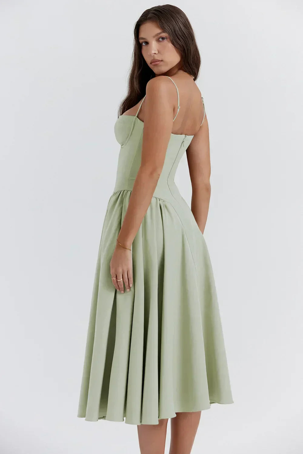 Abito midi verde salvia elegante, donna di profilo, spalline sottili, gonna svasata, moda femminile, abbigliamento estivo, stile sofisticato.