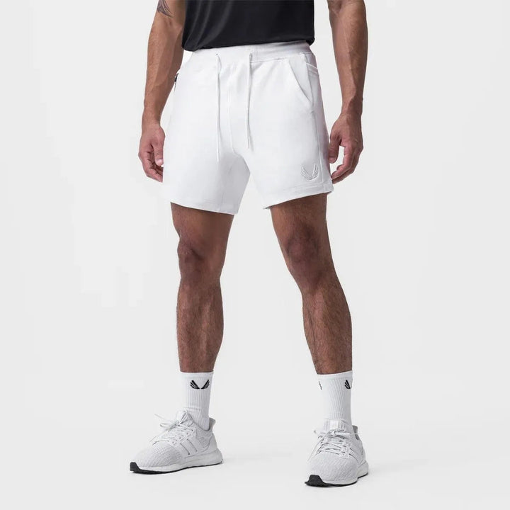 Shorts sportivi bianchi da uomo, design moderno, tasche laterali, indossati con calzini e scarpe da ginnastica bianche. Ideali per allenamento e tempo libero.