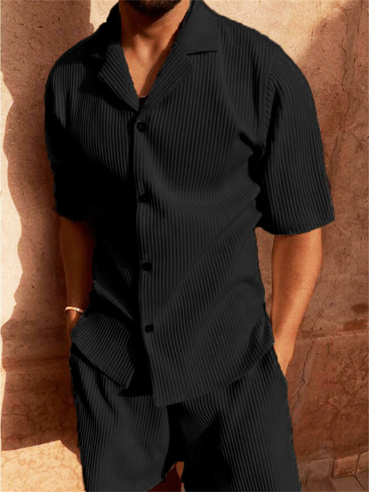 Camicia nera a righe verticali, maniche corte, indossata da uomo. Moda estiva elegante, abbigliamento casual maschile. Sfondo muro beige.