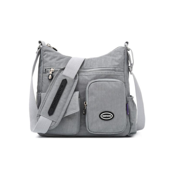 Borsa a tracolla grigia in nylon impermeabile con tasche multiple e cerniere, ideale per viaggi e uso quotidiano. Design pratico e resistente.