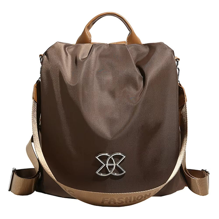 Zaino moda marrone in nylon con manico superiore, tracolla regolabile e decorazione metallica frontale. Accessorio elegante e funzionale per donna.