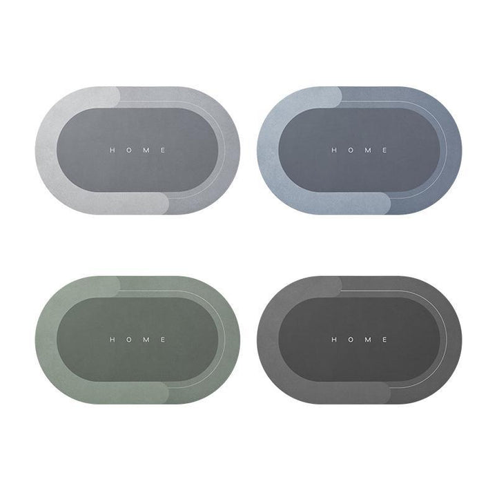 Quattro tappetini ovali antiscivolo in diverse tonalità di grigio e verde, con scritta "HOME" al centro. Ideali per ingresso o cucina.