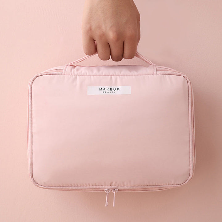 Borsa trucco rosa con manico, chiusura a zip, design compatto. Ideale per organizzare cosmetici e accessori di bellezza.