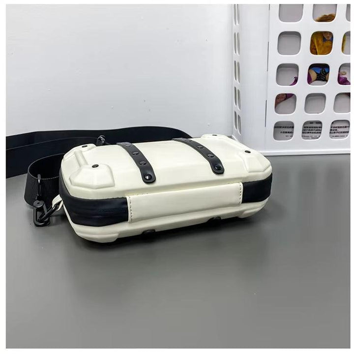 Borsa a tracolla bianca e nera su tavolo grigio, design moderno con cinghie regolabili. Accessorio moda unisex, ideale per uso quotidiano.