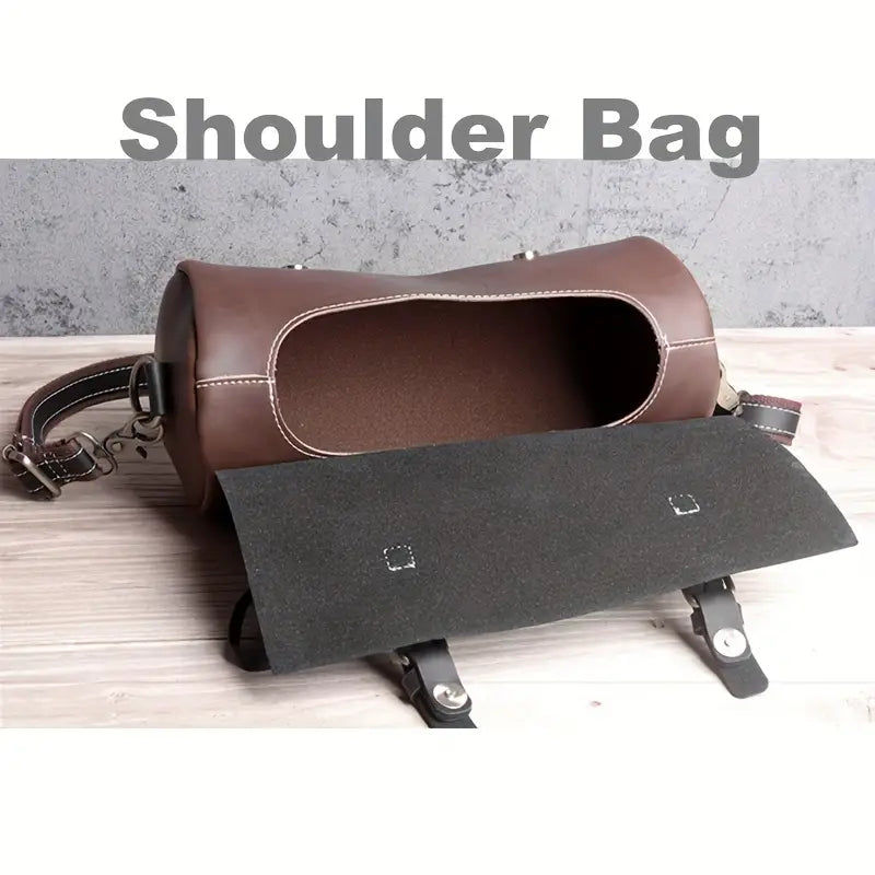 Borsa a tracolla in pelle marrone aperta su sfondo grigio, con cinghie regolabili e chiusura a fibbia. Design elegante e spazioso.
