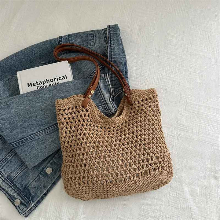 Borsa a rete in paglia con manici in pelle su jeans e libro, moda estiva, accessori donna, stile casual chic, tendenze 2023.