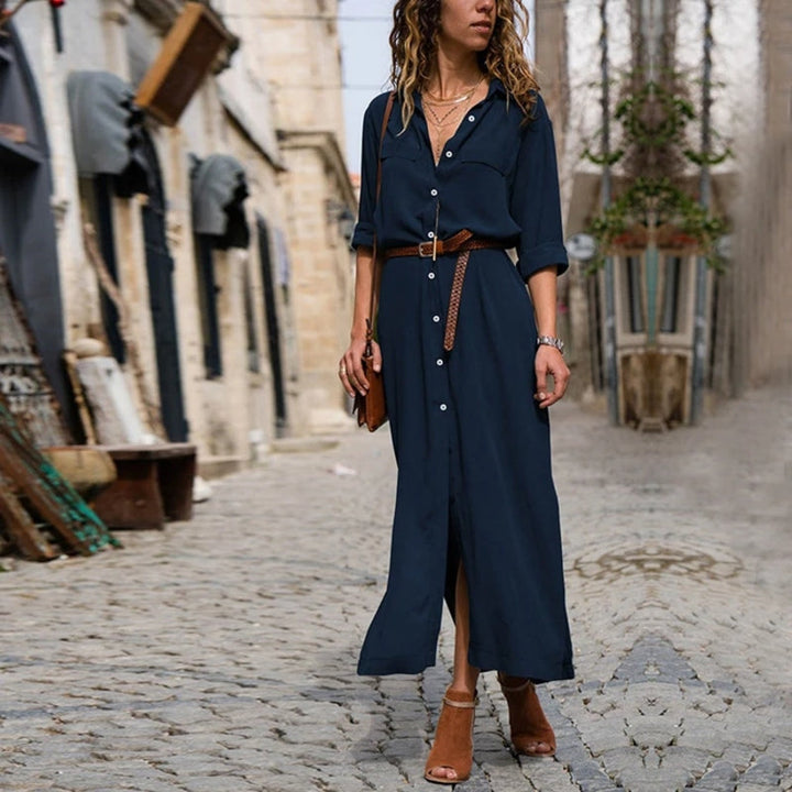Donna con abito lungo blu e cintura marrone cammina su strada acciottolata. Moda urbana, stile casual chic, abbigliamento estivo elegante.
