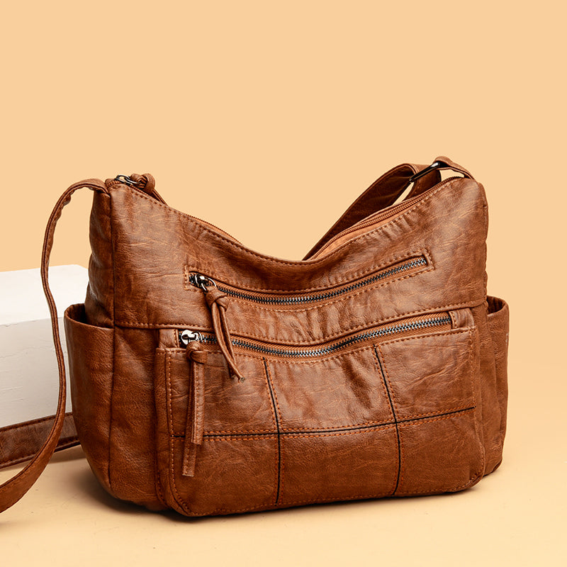 Borsa a tracolla in pelle marrone con tasche multiple e cerniere, design elegante e pratico, ideale per uso quotidiano e moda femminile.