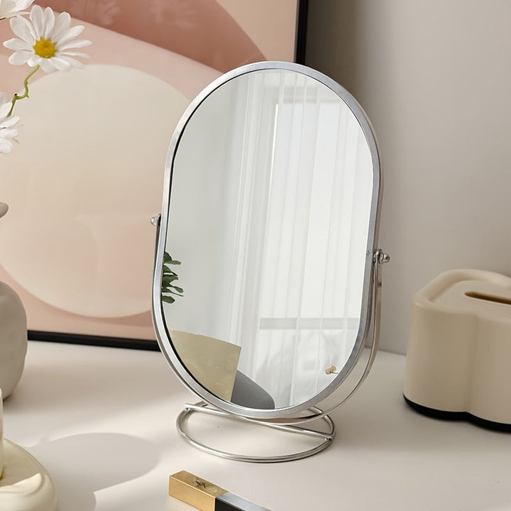 Specchio da tavolo ovale con cornice in metallo, riflesso di interni moderni, decorazione minimalista, luce naturale, vaso con margherite.