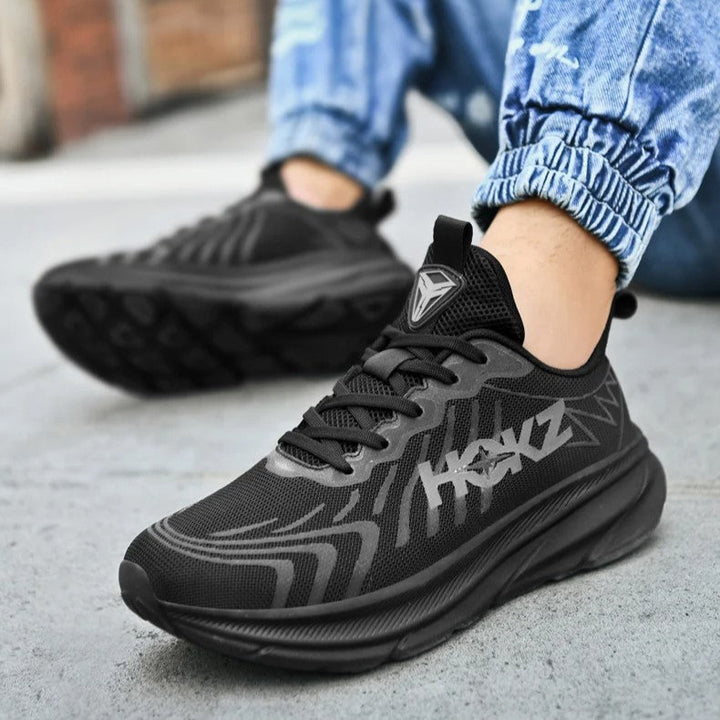 Scarpe da ginnastica nere da uomo, design moderno, suola ammortizzata, indossate con jeans. Scarpe sportive casual per corsa e tempo libero.