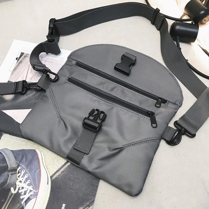 Marsupio grigio unisex in nylon con cerniere multiple e fibbie regolabili, ideale per viaggi e attività all'aperto. Design moderno e funzionale.