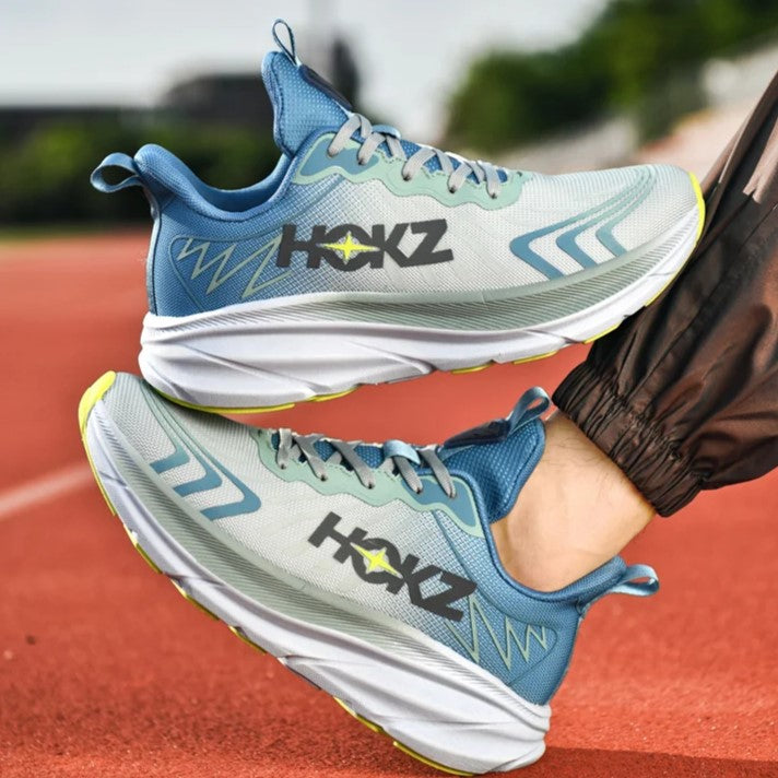 Scarpe da corsa HOKZ su pista rossa, design moderno blu e grigio, suola ammortizzata, ideali per running e sport all'aperto.