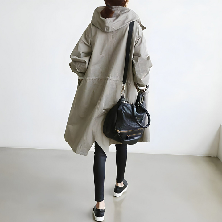 Donna con cappotto beige oversize, leggings neri e borsa a tracolla in pelle nera. Moda casual autunnale, abbigliamento urbano elegante.